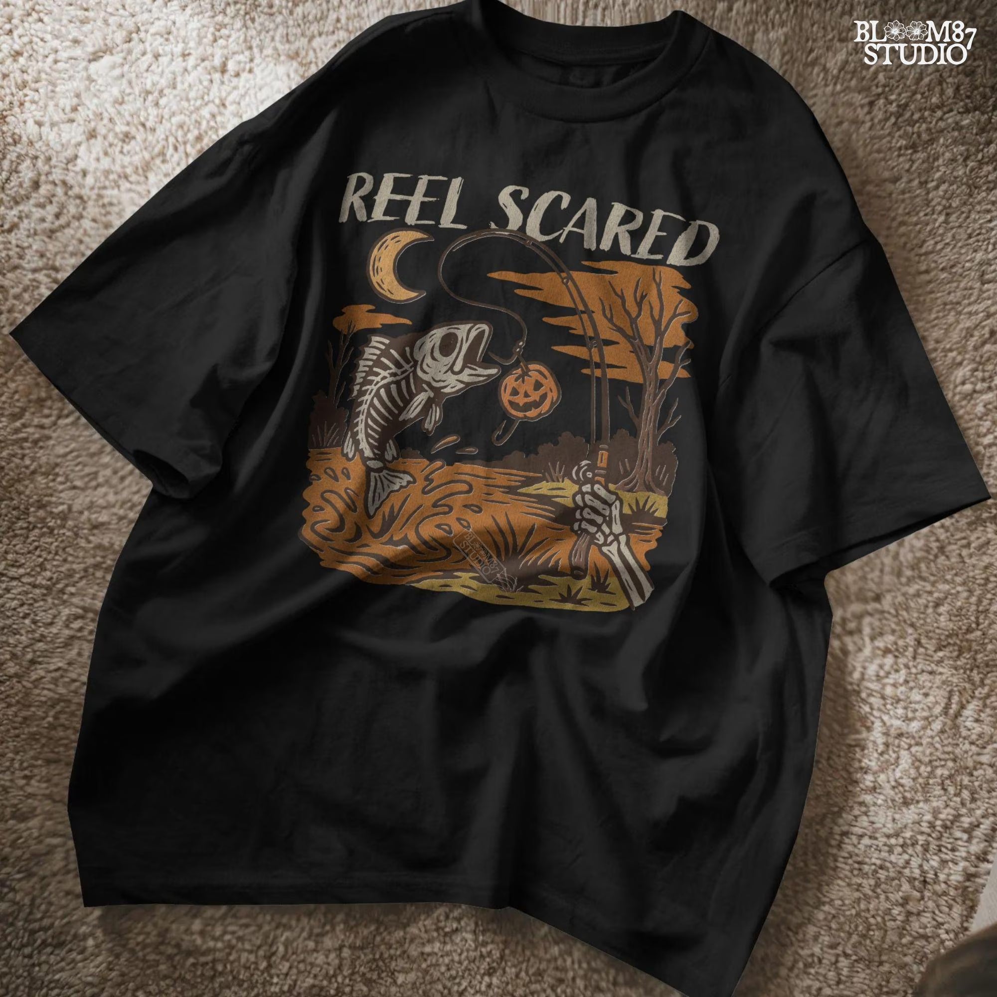 Black t-shirt with 'Reel Scared' graphic design on a textured surface