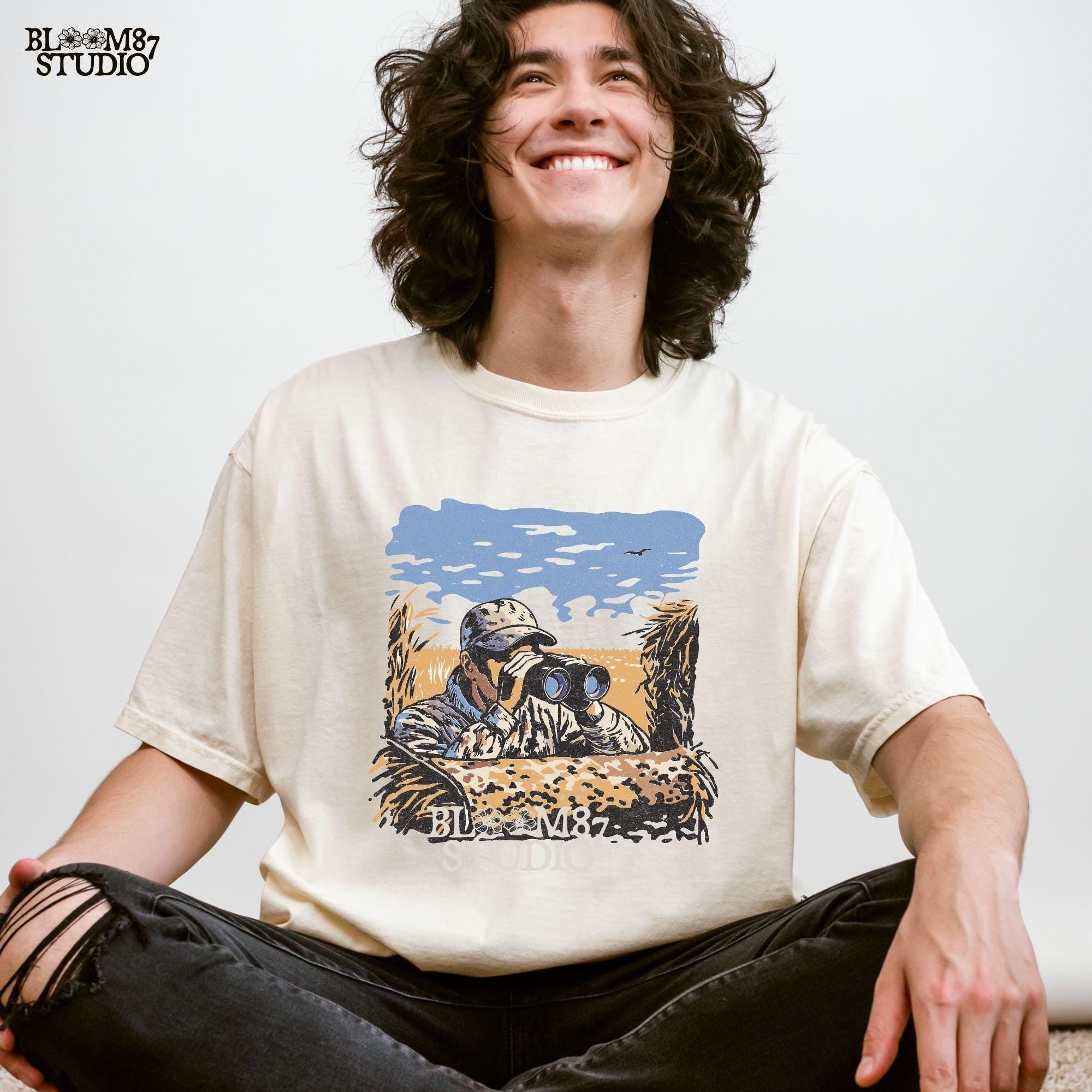 “Illustrated camouflage hunter peeking through binoculars from a duck blind, surrounded by tall grass, with a blue sky and golden field background. A detailed digital hunting-themed design, perfect for outdoorsmen, wildlife lovers, and hunting gear.”