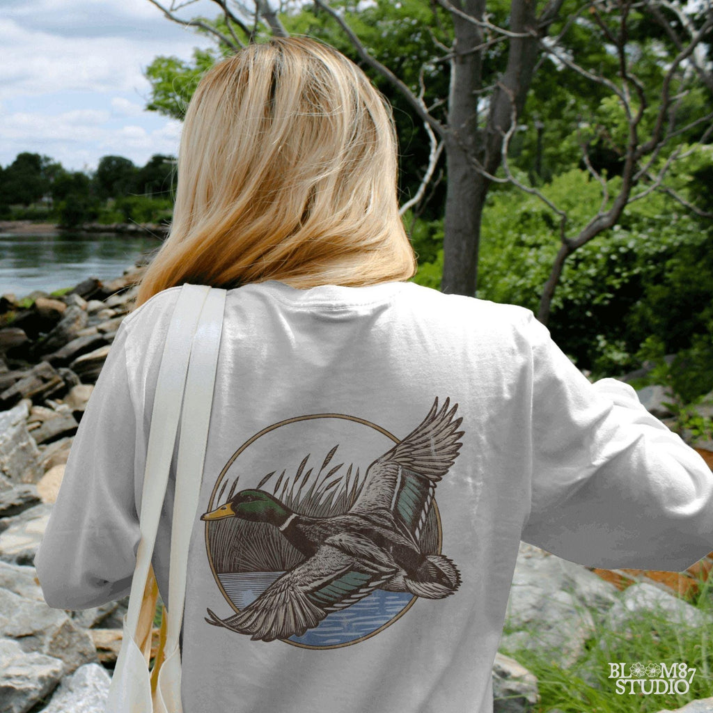 "Vintage flying mallard duck PNG clipart in marsh scene, rustic wildlife sublimation design for duck hunting shirts and outdoor gear"