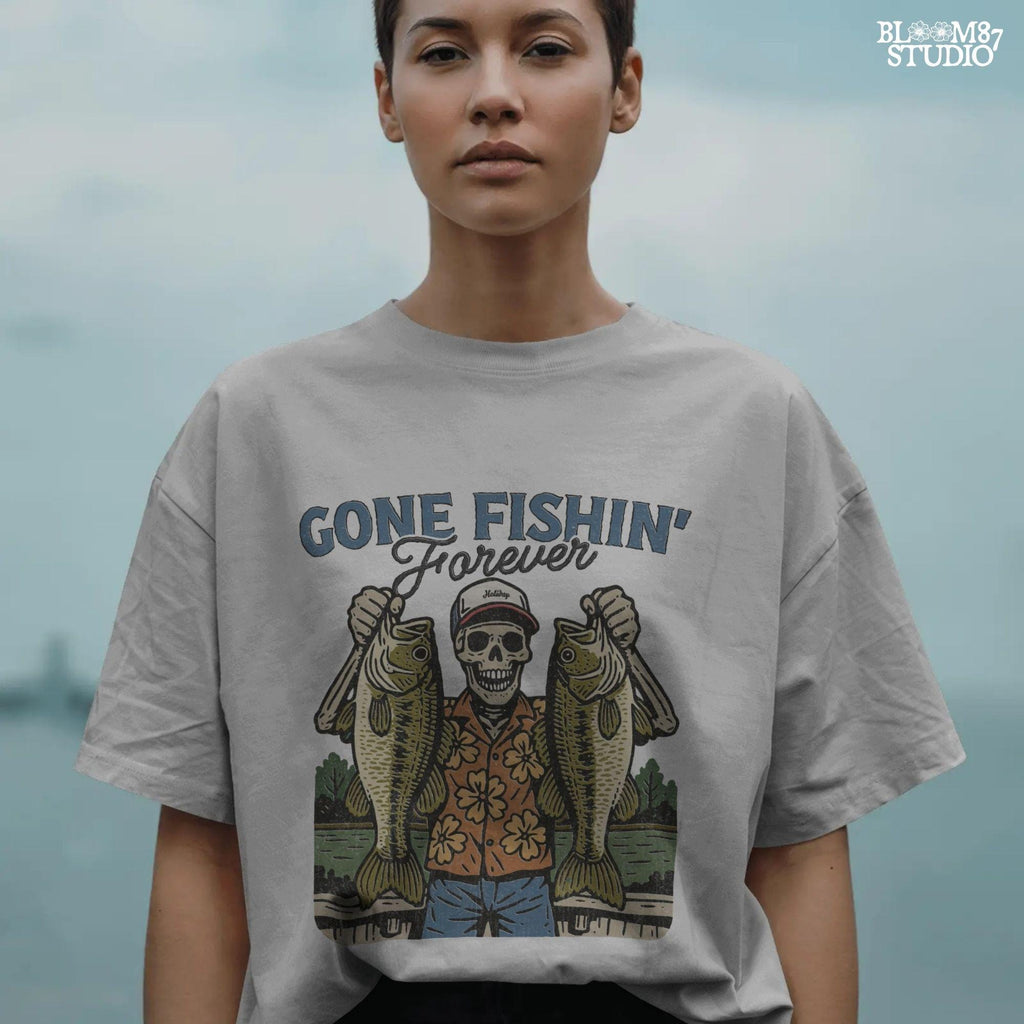 A skeleton wearing a red cap and orange floral shirt stands on a dock holding two large bass fish with the words “Gone Fishin’ Forever” above.