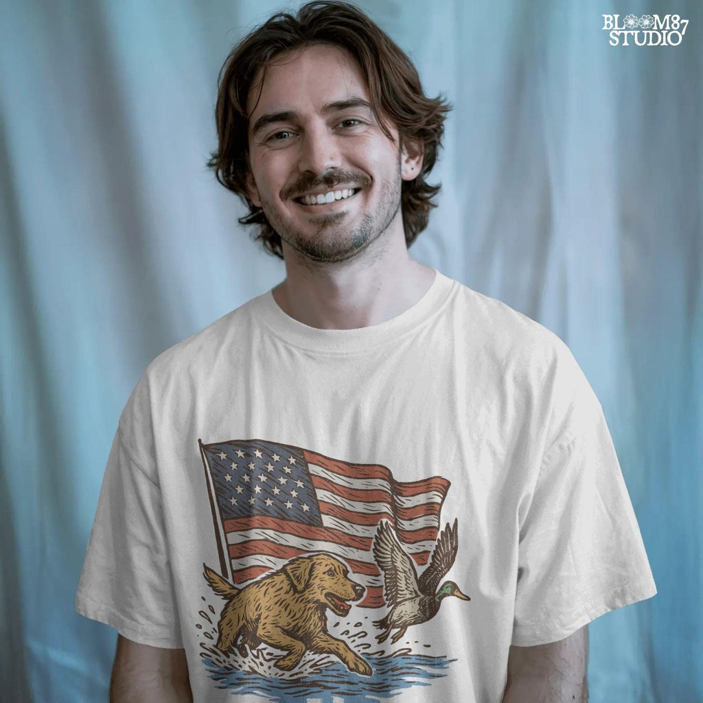 A yellow Labrador retriever splashing in water next to a flying duck, with a waving American flag in the background.