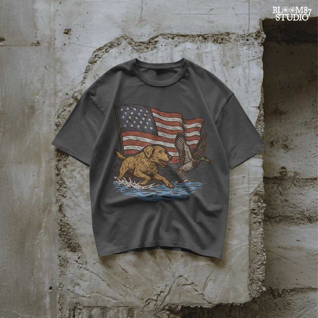 A yellow Labrador retriever splashing in water next to a flying duck, with a waving American flag in the background.