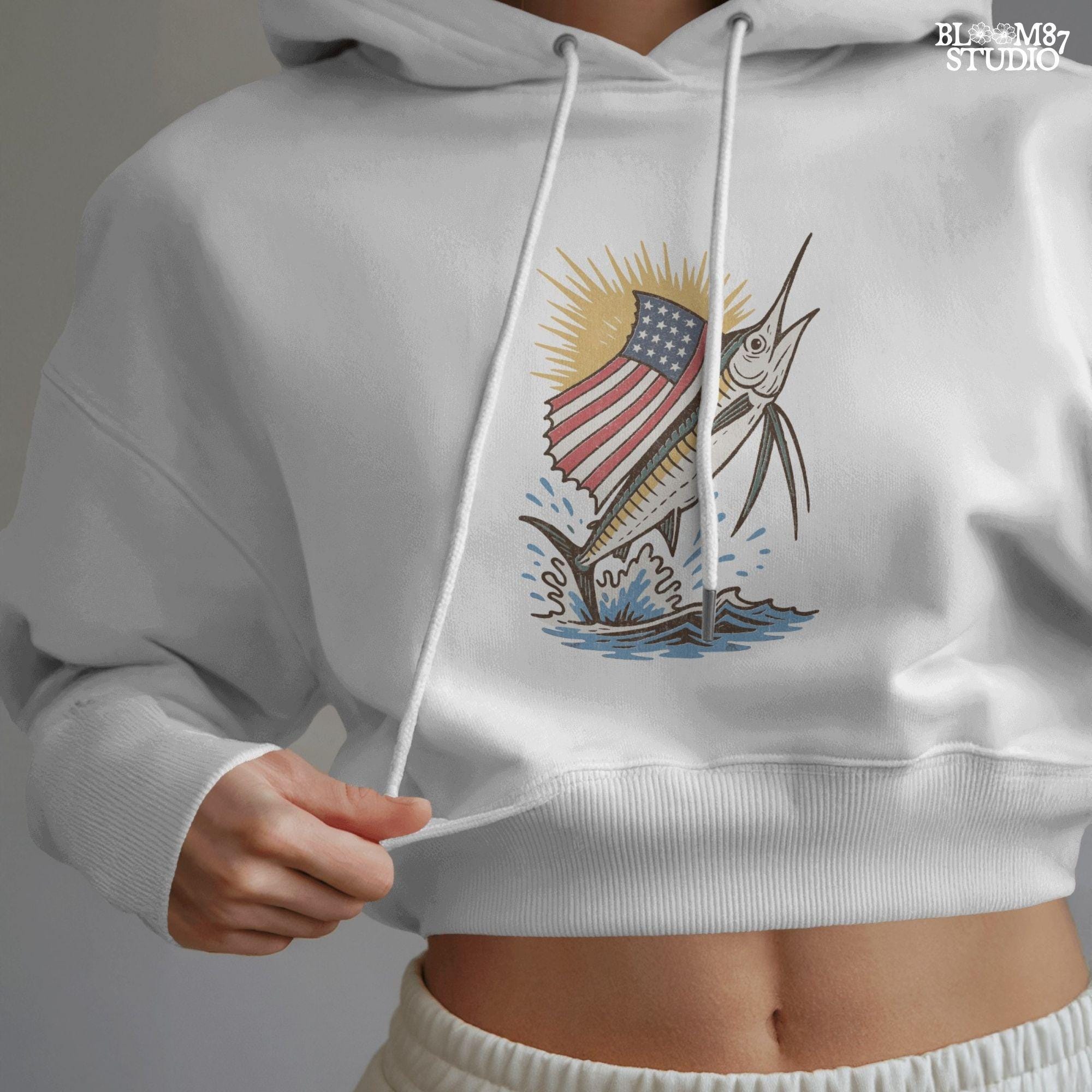 A jumping marlin with a large sail shaped like the American flag, splashing out of the ocean with sun rays in the background.