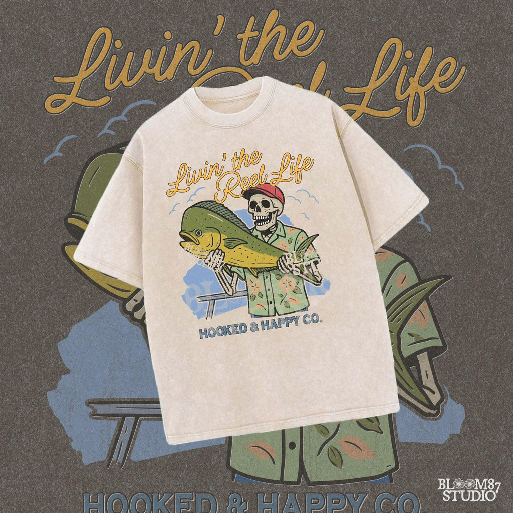 Cartoon skeleton in tropical shirt holding a mahi-mahi fish with text “Livin’ the Reel Life” above and “Hooked & Happy Co.” below.