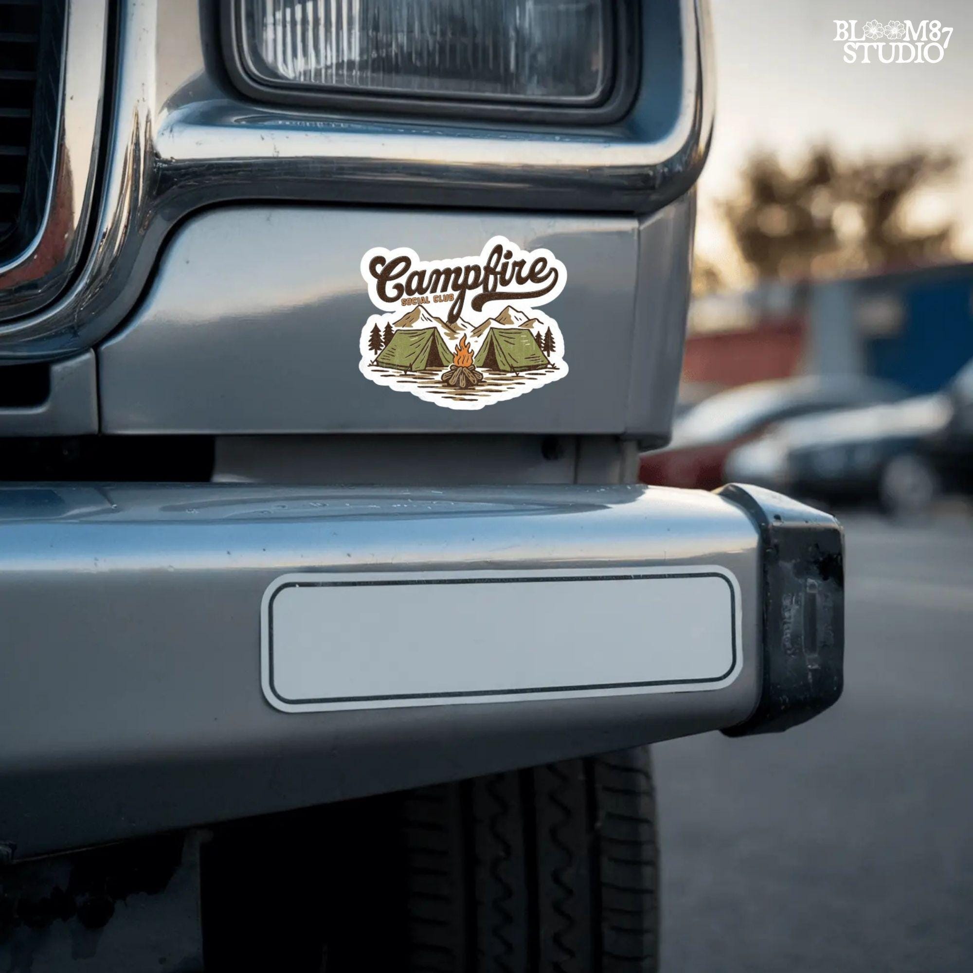 Vintage-style illustration of two camping tents, a lit campfire, pine trees, and mountains with the text “Campfire Social Club.”