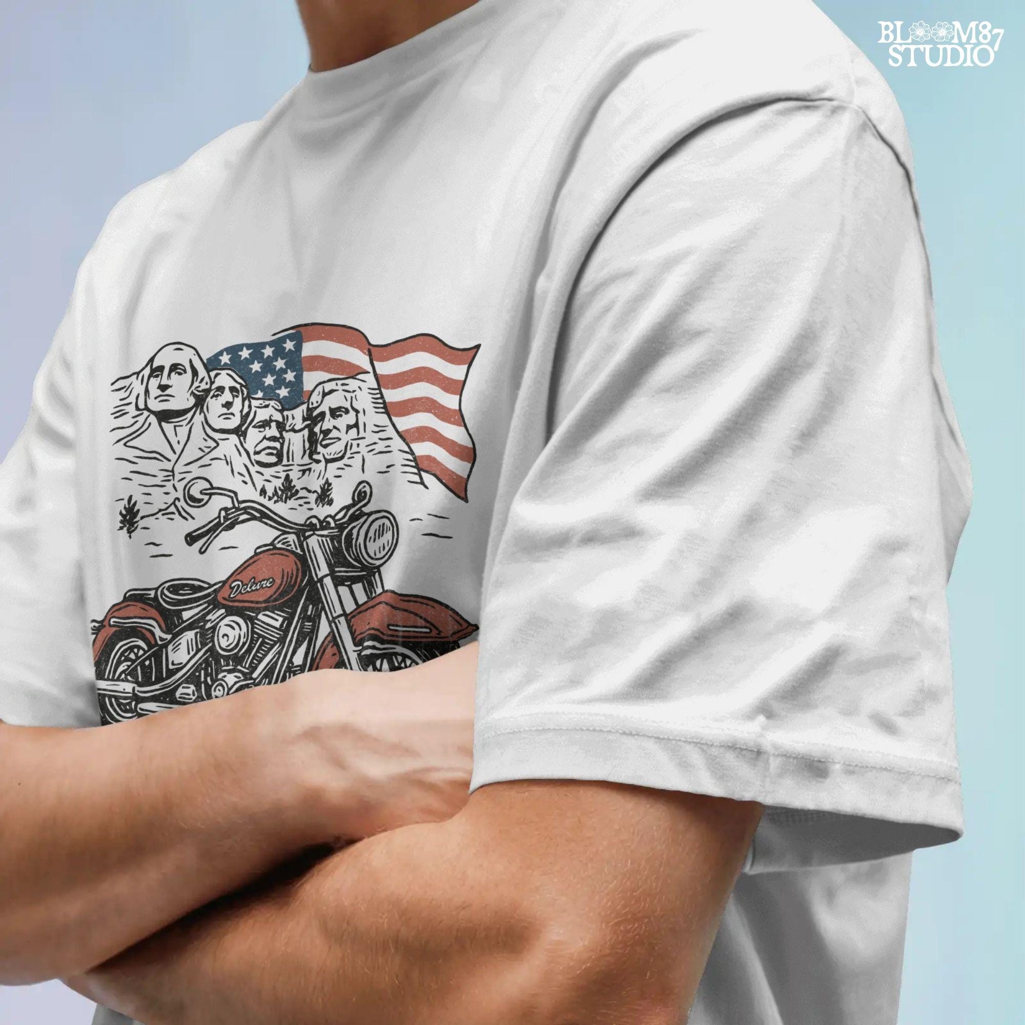 Vintage motorcycle graphic in front of Mount Rushmore and a waving American flag, styled in patriotic colors with retro biker design elements.