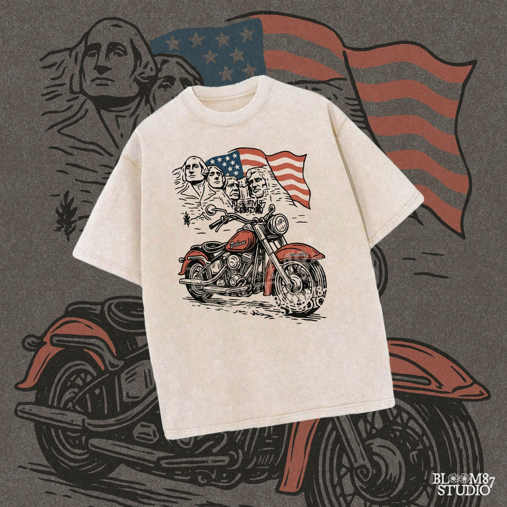 Vintage motorcycle graphic in front of Mount Rushmore and a waving American flag, styled in patriotic colors with retro biker design elements.