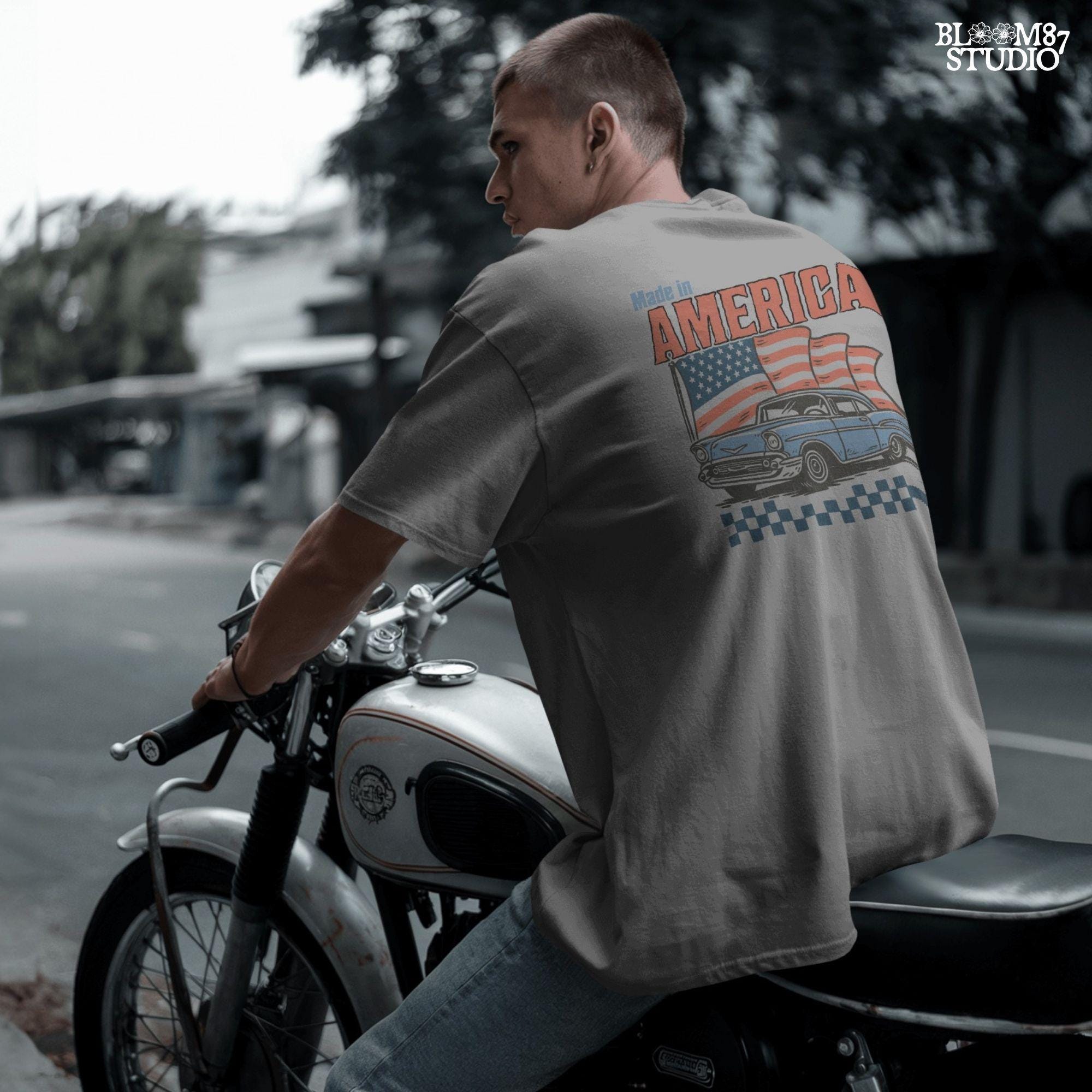 Classic American vintage car driving in front of three waving USA flags with “Made in America” text in bold retro style.