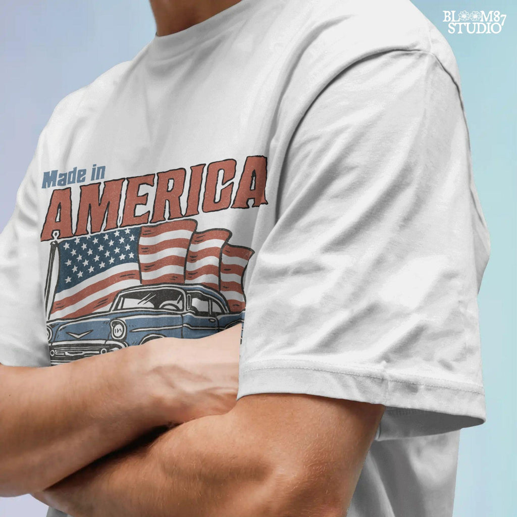 Classic American vintage car driving in front of three waving USA flags with “Made in America” text in bold retro style.