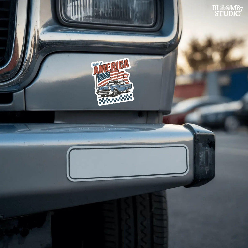 Classic American vintage car driving in front of three waving USA flags with “Made in America” text in bold retro style.