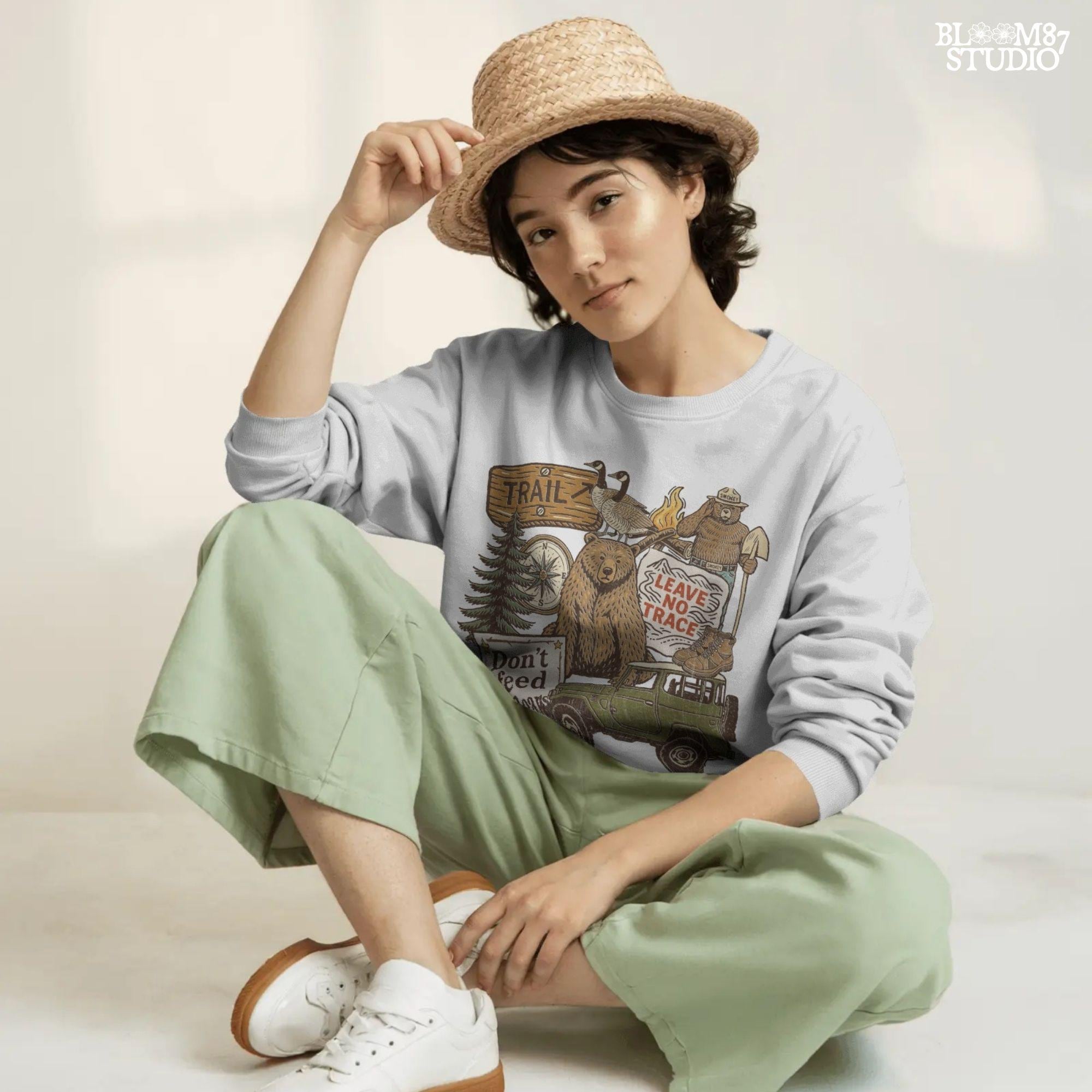 Illustration of a camping-themed collage featuring a grizzly bear, “Leave No Trace” sign, Smokey the Bear, trail sign, compass, boots, a green jeep, and forest scenery.