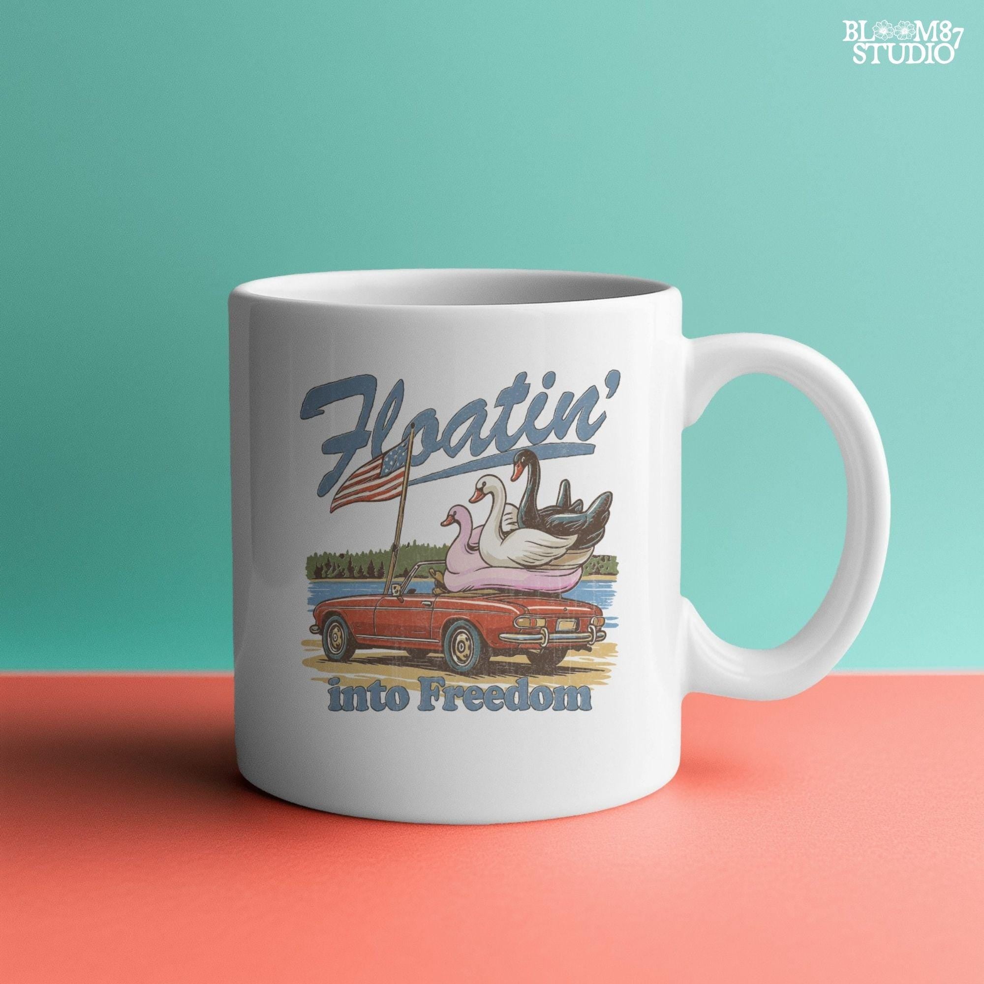 A red convertible car on the beach carrying three swan pool floats with an American flag, with the text “Floatin’ into Freedom” in a playful patriotic theme.