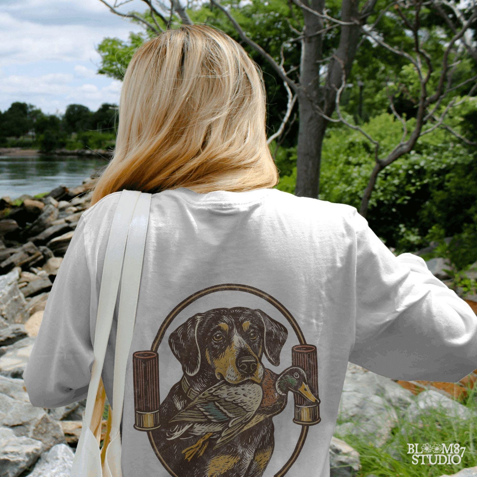 "Duck hunting dog PNG with mallard and shotgun shells, vintage retriever badge style sublimation for hunting shirt designs"