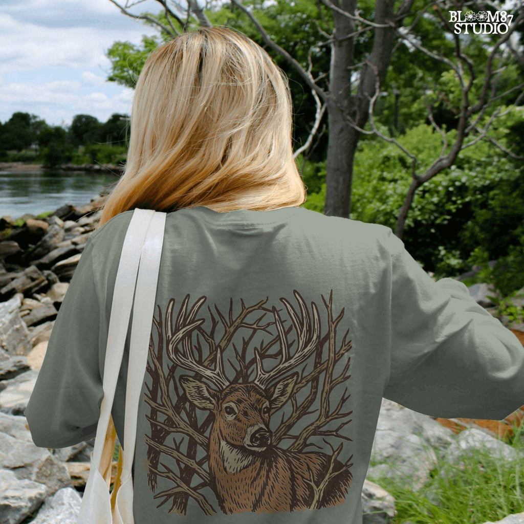 Hand-drawn whitetail deer with large antlers surrounded by bare woodland branches in earthy brown tones on a transparent background.
