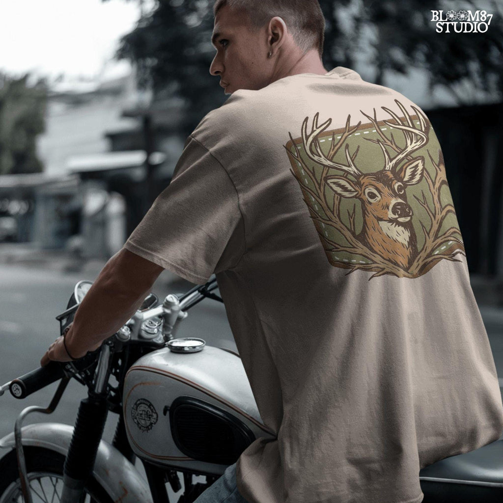 Stylized deer head with antlers framed by bare branches, placed on an olive green patch background with stitching detail.
