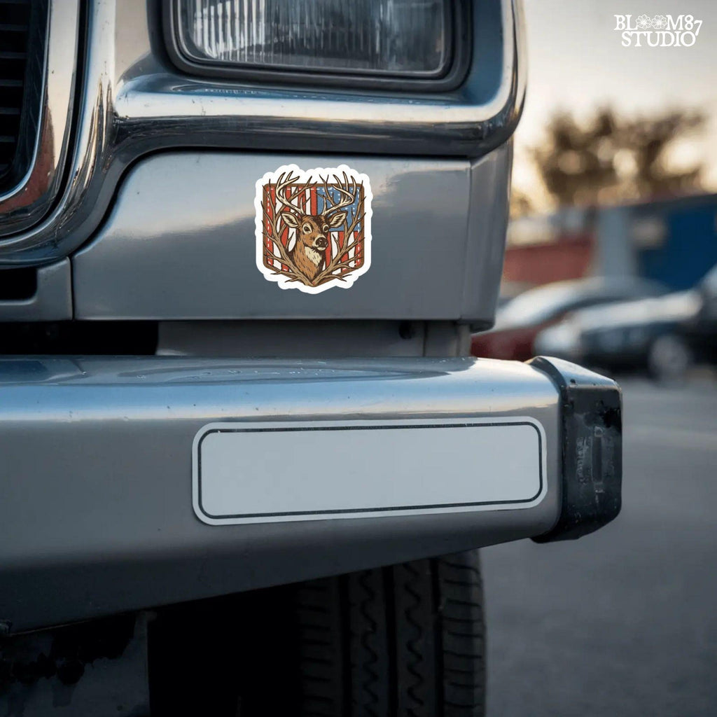 Illustration of a proud buck with large antlers standing in front of a stitched American flag patch, rustic hunting style.