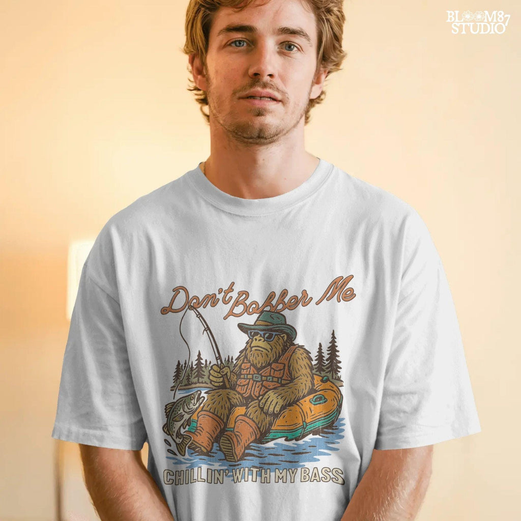 Funny Bigfoot sitting in a float tube holding a fishing rod and bass fish, wearing sunglasses and vest, with text “Don’t Bobber Me – Chillin’ with My Bass.”