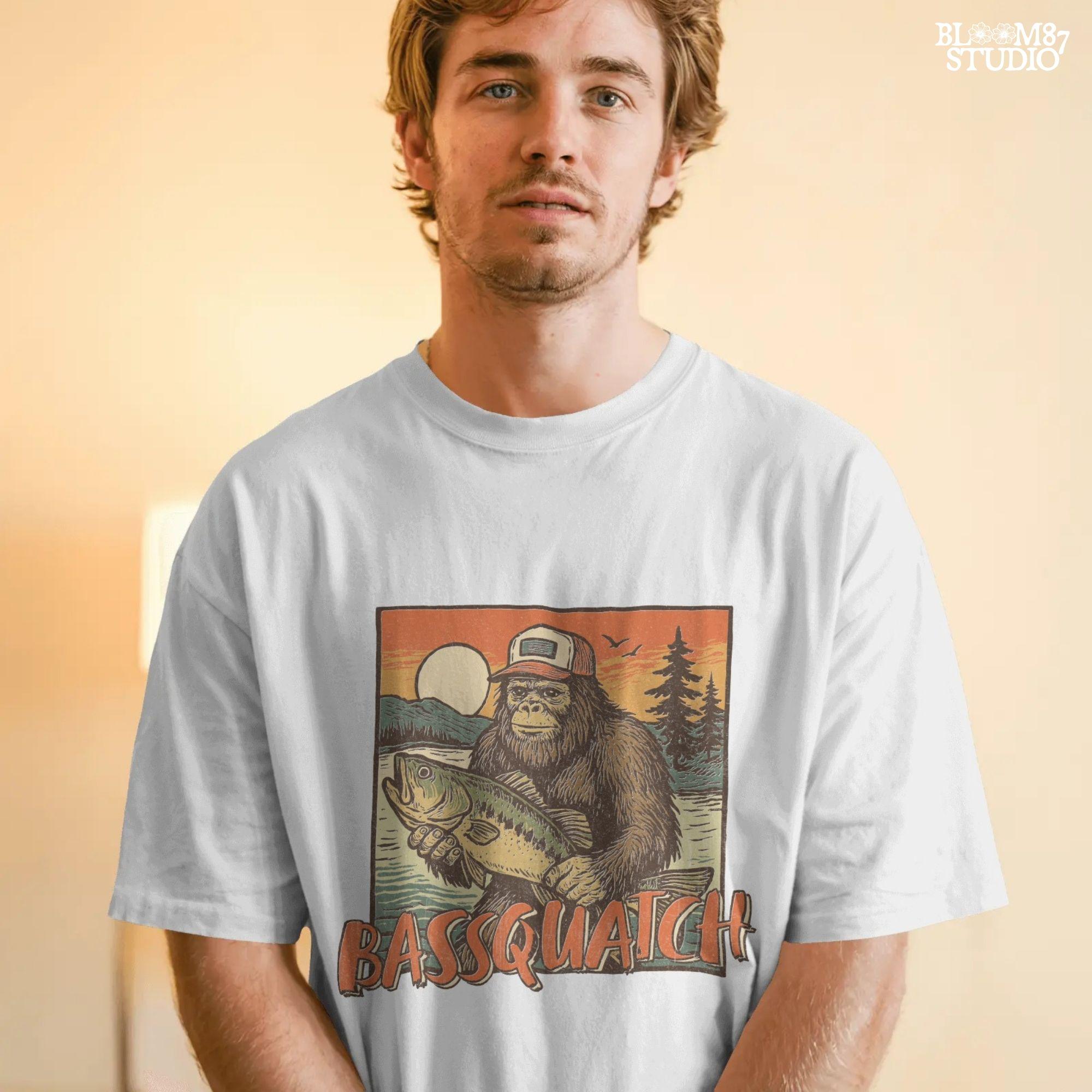 Bigfoot holding a large bass at sunset with summer lake background and the word “Bassquatch” in bold orange letters.