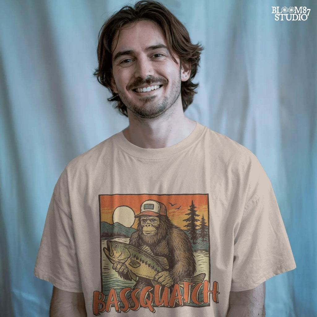 Bigfoot holding a large bass at sunset with summer lake background and the word “Bassquatch” in bold orange letters.