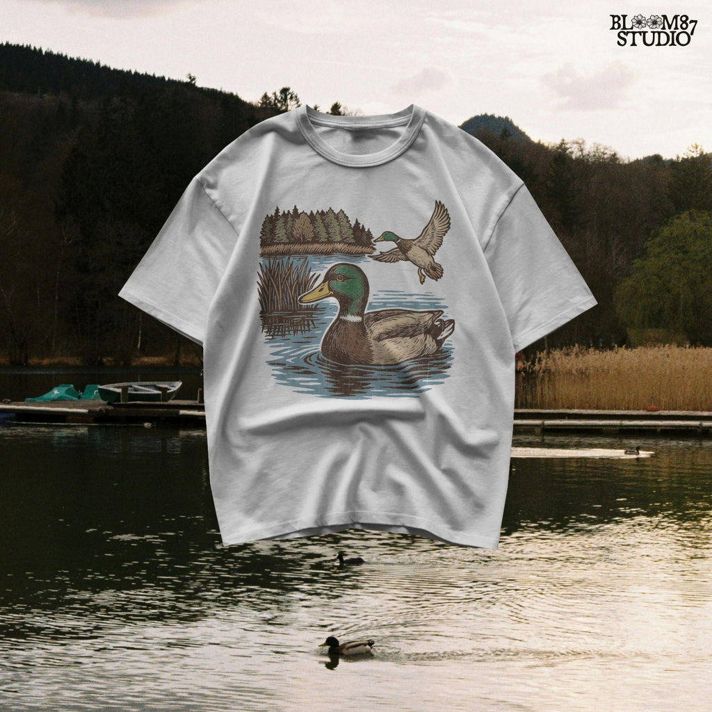 Two mallard ducks in a peaceful summer lake scene with pine trees and blue water, one swimming and one flying.
