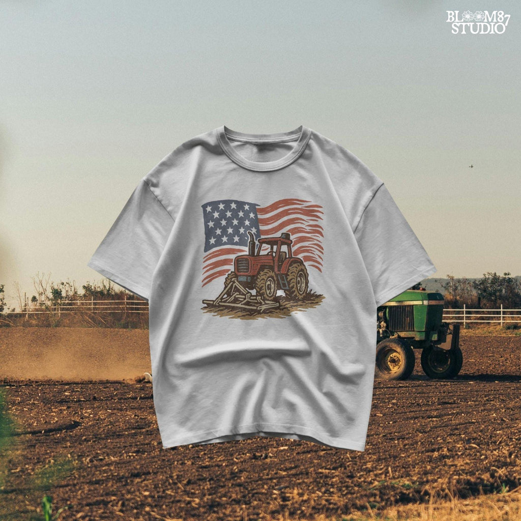 Red tractor with plow on soil, American flag waving in the background, vintage farm-themed graphic.