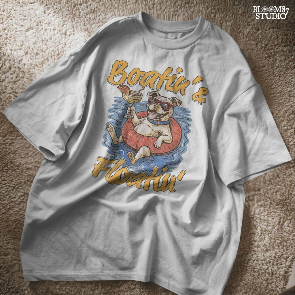 Cartoon bulldog in red sunglasses floating on a tube, holding a margarita, with “Boatin’ & Floatin’” summer text.