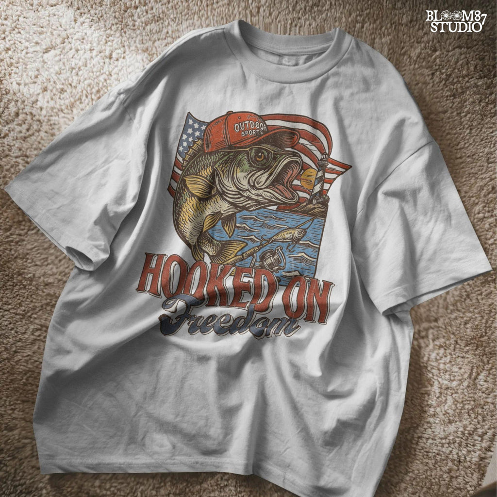 Patriotic bass fish wearing red cap with American flag, lighthouse, and “Hooked on Freedom” text – ideal for 4th of July fishing designs.