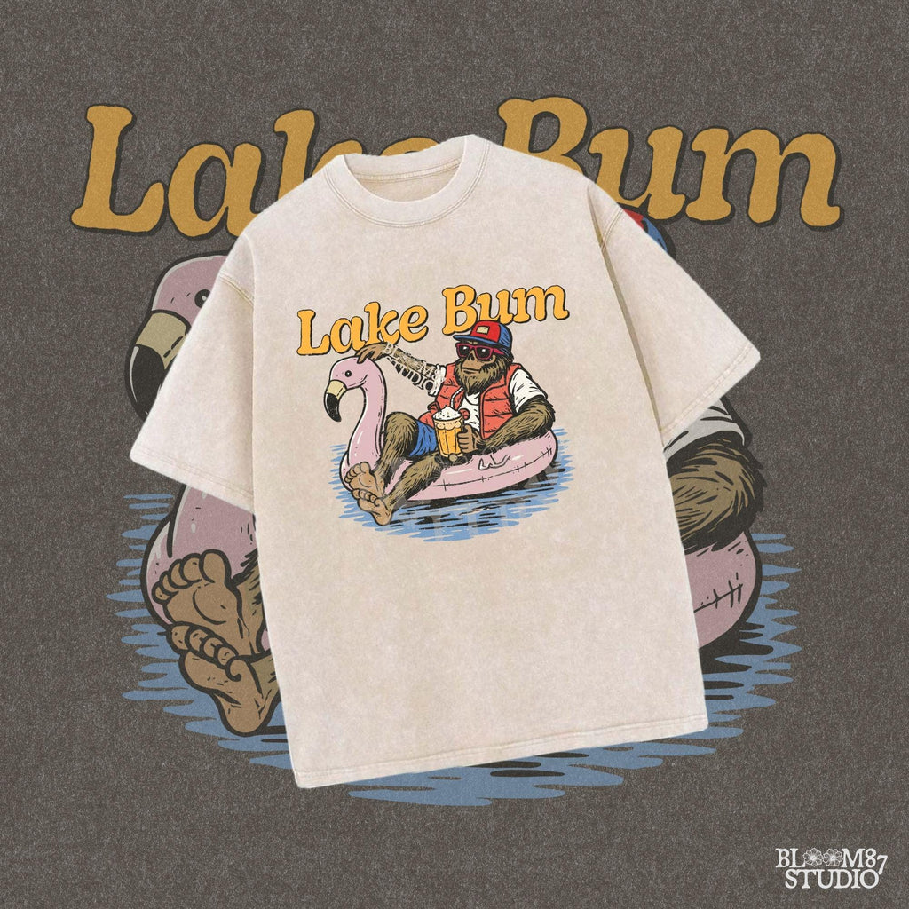 Bigfoot lounging on a pink flamingo float with a beer, wearing summer gear and sunglasses, with “Lake Bum” text above.