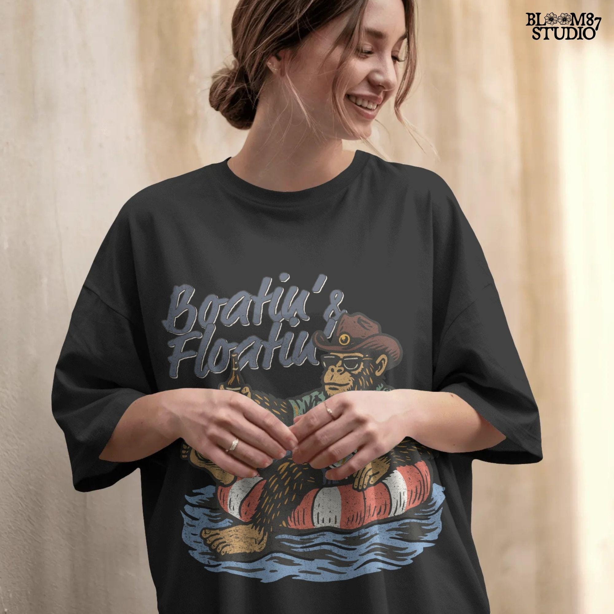 Bigfoot relaxing in a red and white pool float, holding a beer and wearing sunglasses, a hat, and a tropical shirt with “Boatin’ & Floatin’” text above.