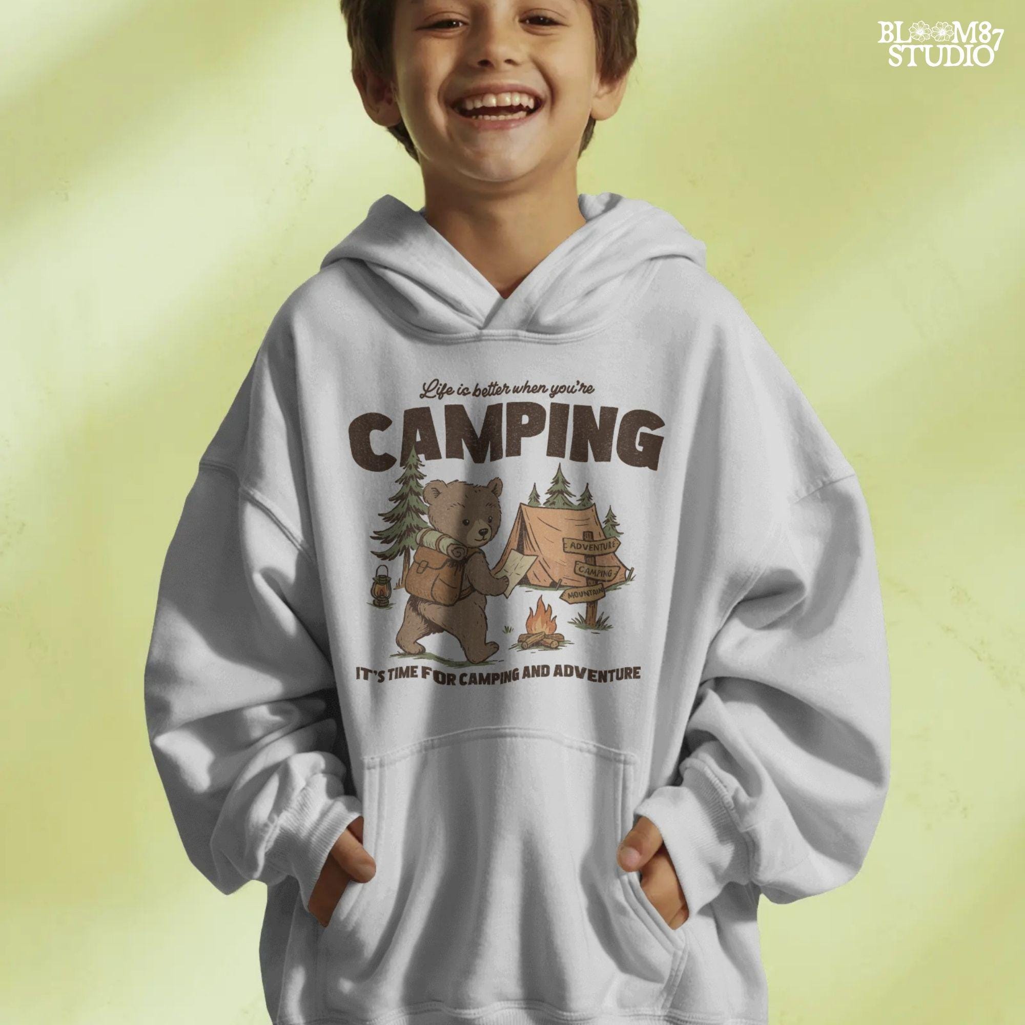 Cute bear with a backpack and camping map standing by a tent, campfire, and wooden adventure signs in a forest scene.