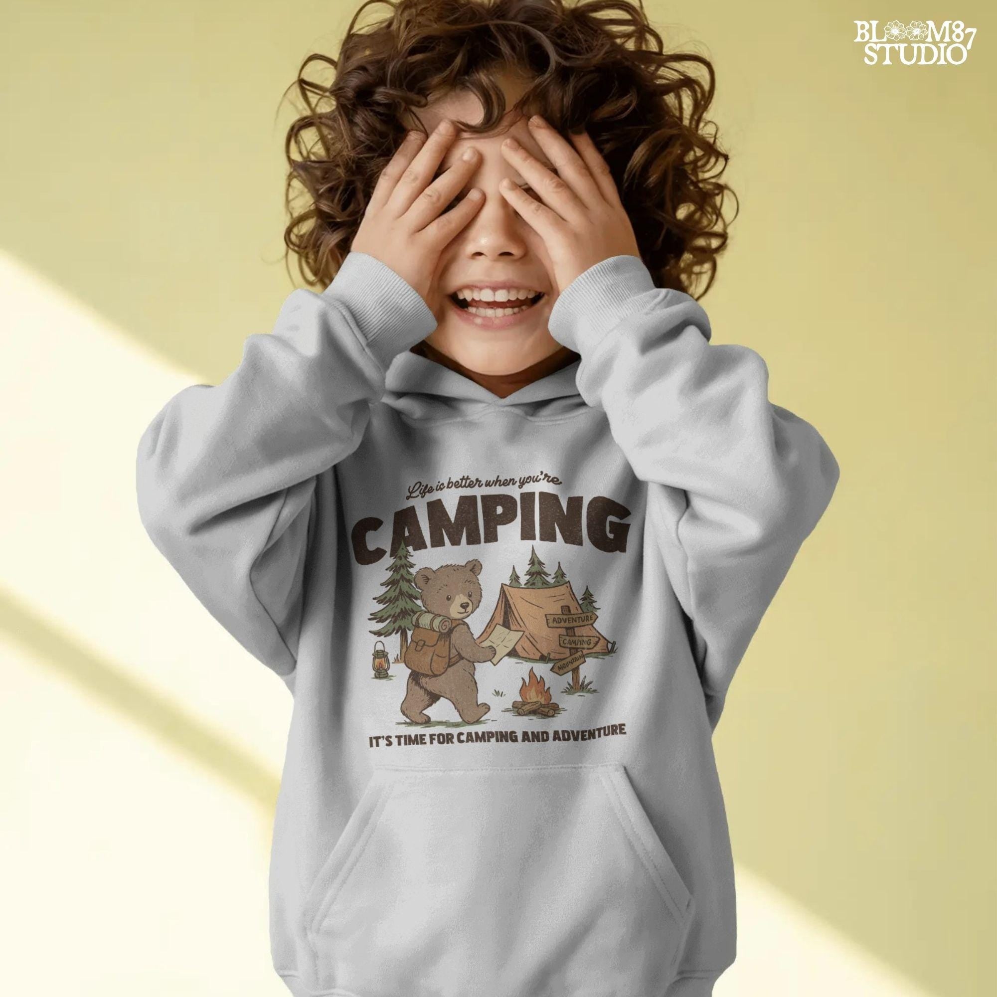 Cute bear with a backpack and camping map standing by a tent, campfire, and wooden adventure signs in a forest scene.