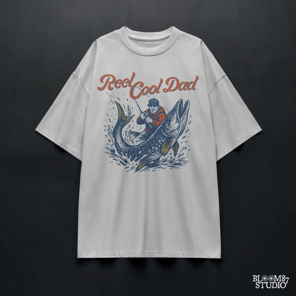 Illustration of a father reeling in a giant fish with bold text “Reel Cool Dad,” perfect for Father’s Day or fishing-themed gifts.