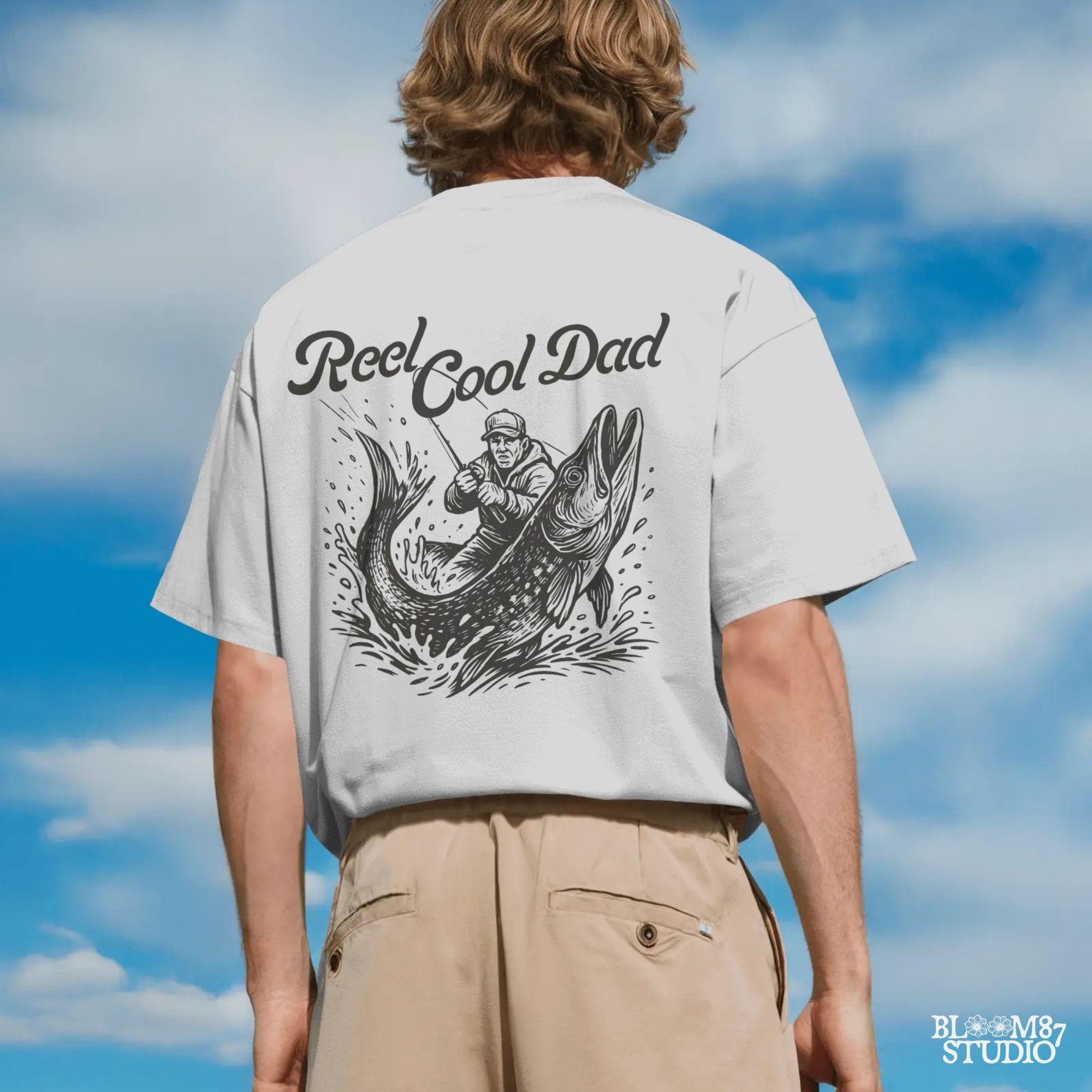 Illustration of a father reeling in a giant fish with bold text “Reel Cool Dad,” perfect for Father’s Day or fishing-themed gifts.