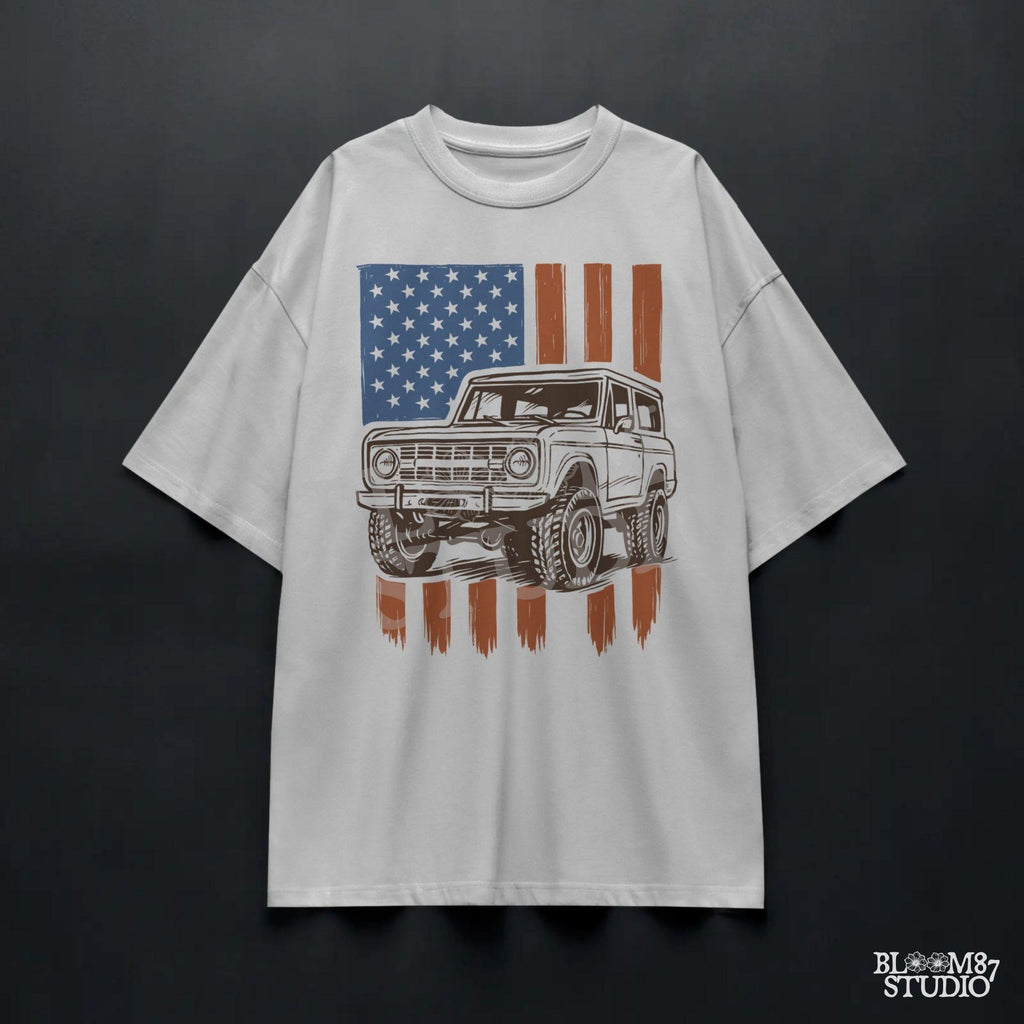 Vintage 4x4 Bronco-style off-road truck with bold tires over a distressed American flag, perfect for patriotic truck lovers and USA-themed designs.