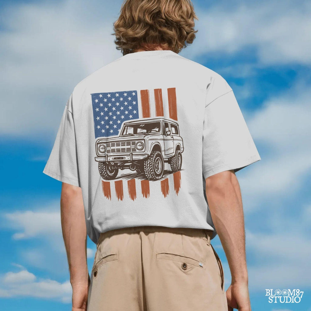 Vintage 4x4 Bronco-style off-road truck with bold tires over a distressed American flag, perfect for patriotic truck lovers and USA-themed designs.