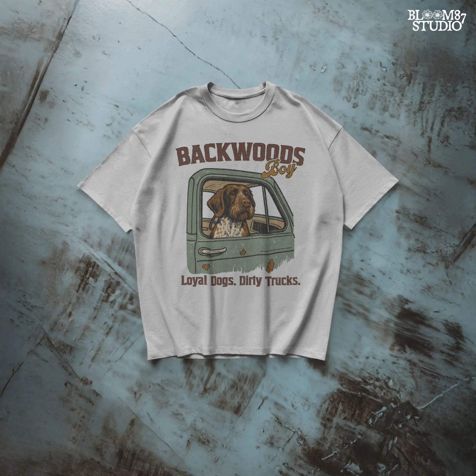 German Wirehaired Pointer hunting dog in rustic truck window with text “Backwoods Boy” and phrase “Loyal Dogs. Dirty Trucks.”