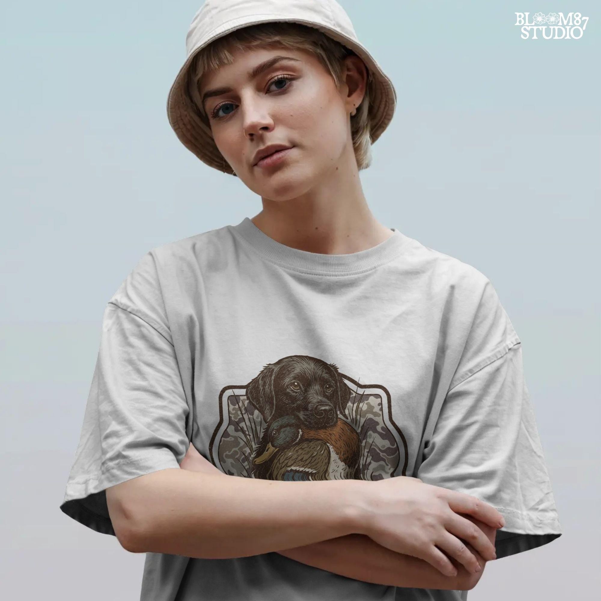 Black Labrador retriever holding a mallard duck with a camouflage background, perfect for hunting or outdoors-themed designs.