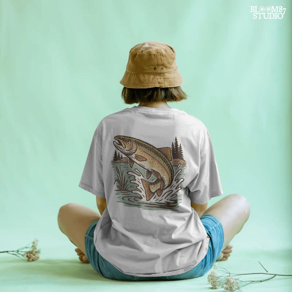 Illustrated trout leaping from the river surrounded by reeds and pine trees, perfect for summer fishing and outdoor adventure designs.