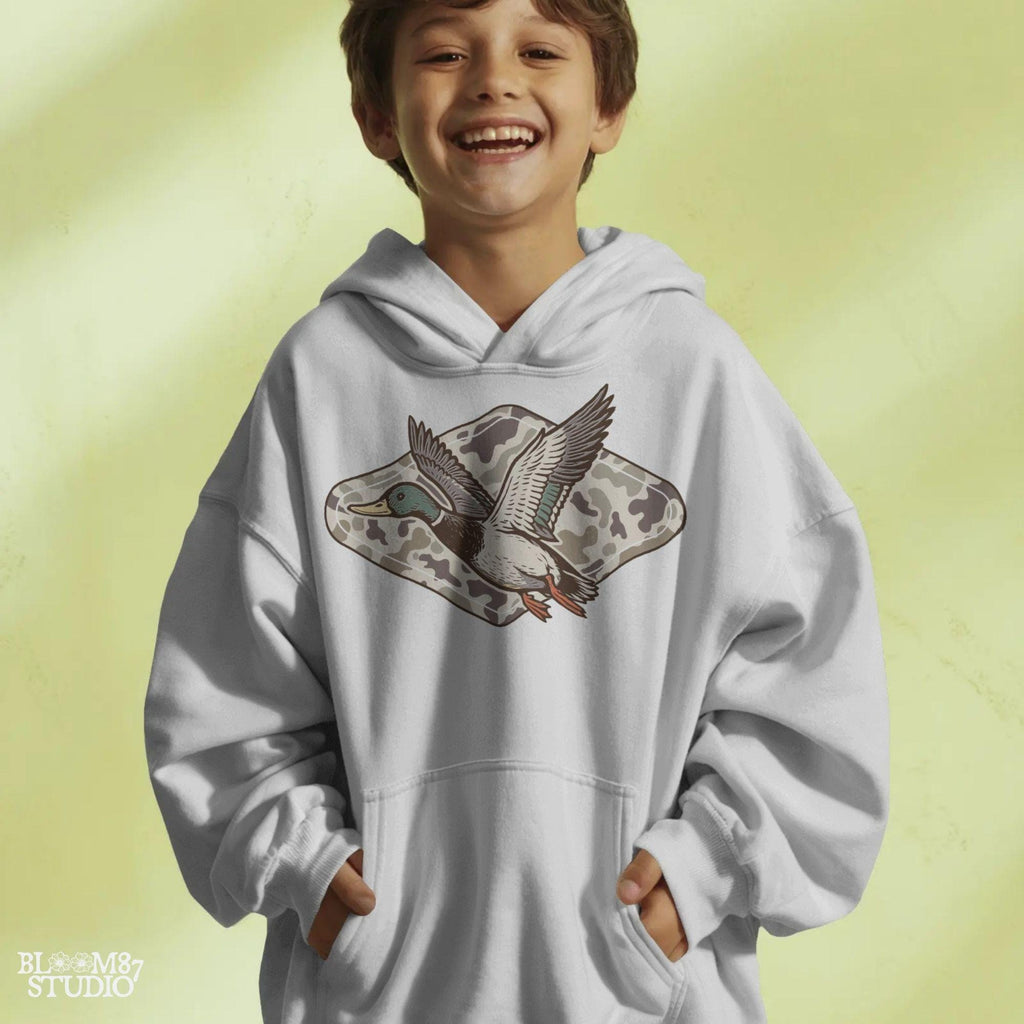 Flying mallard duck over old-school marsh camouflage background, designed in vintage hunting style for southern outdoorsman-themed crafts.