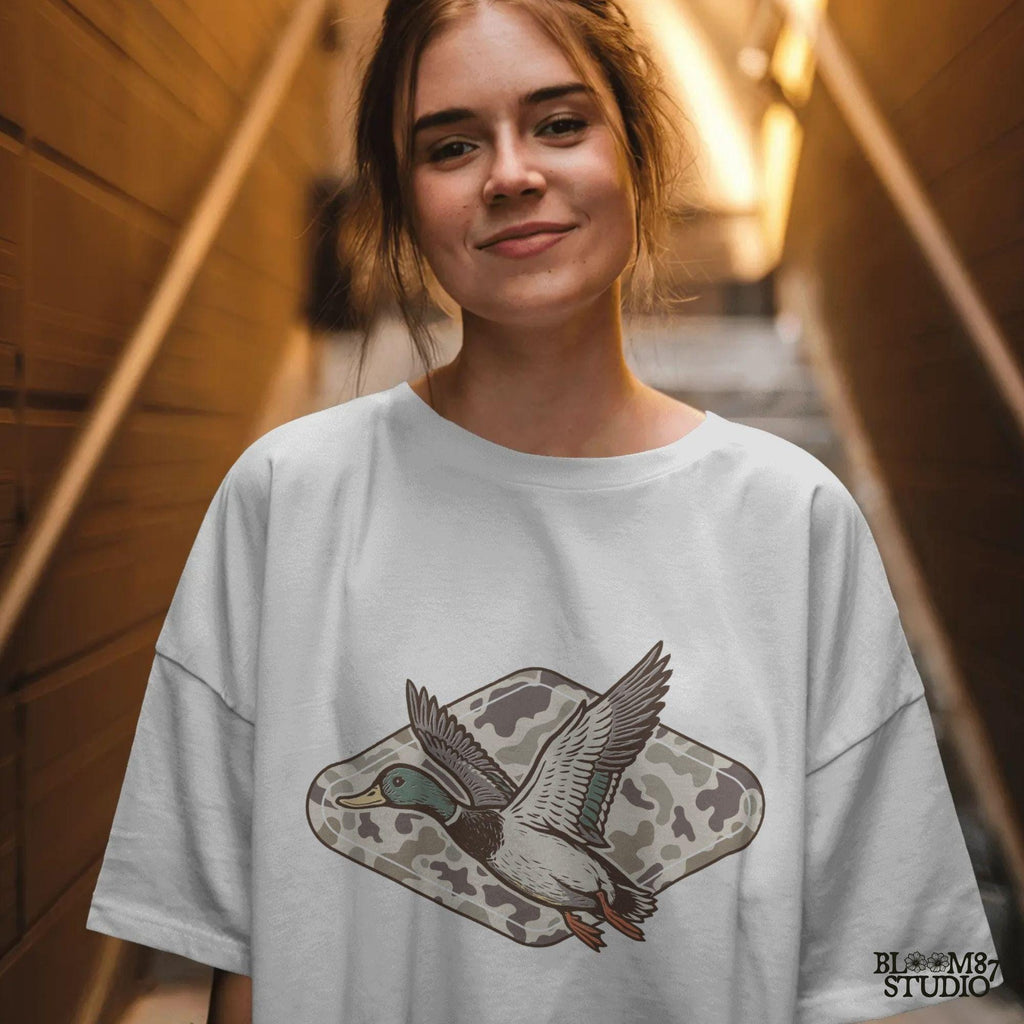 Flying mallard duck over old-school marsh camouflage background, designed in vintage hunting style for southern outdoorsman-themed crafts.