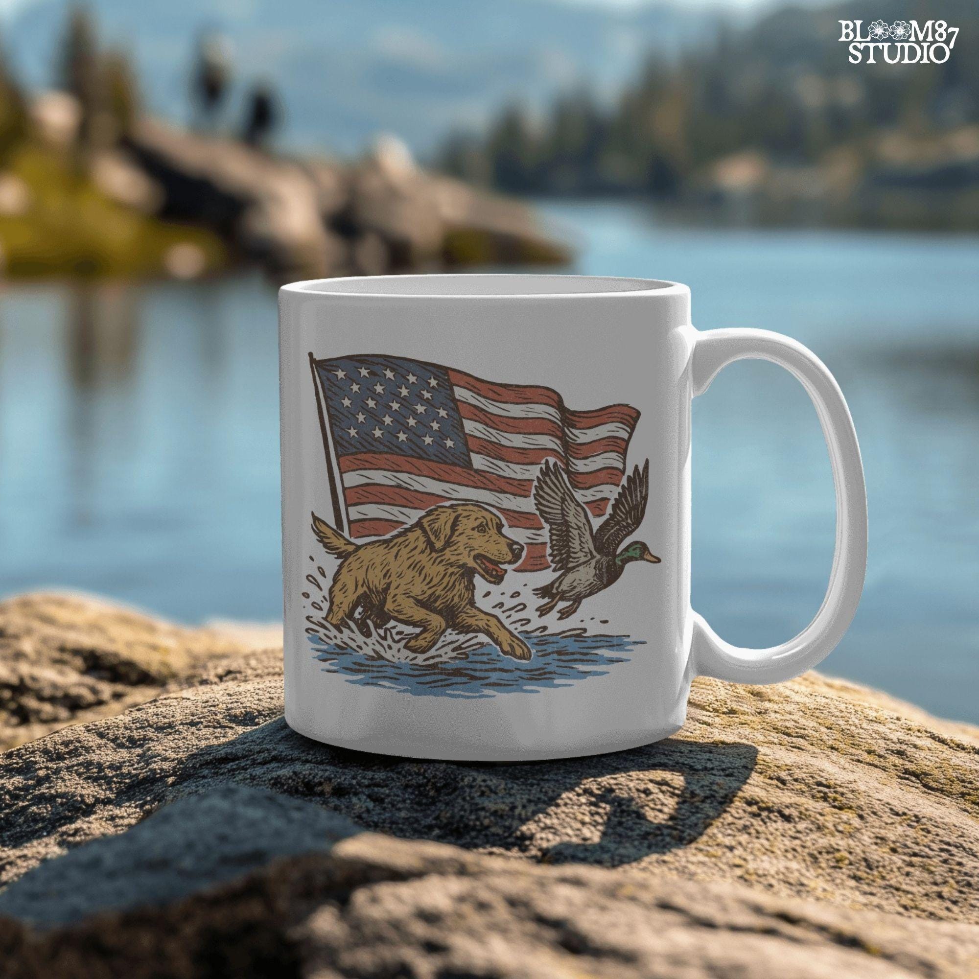 A yellow Labrador retriever splashing in water next to a flying duck, with a waving American flag in the background.