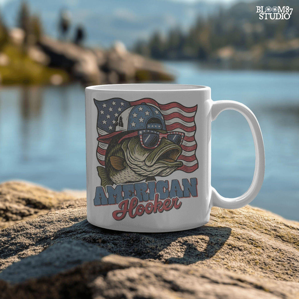 Patriotic cartoon largemouth bass wearing USA sunglasses and a hat in front of the American flag, with the text “American Hooker”.