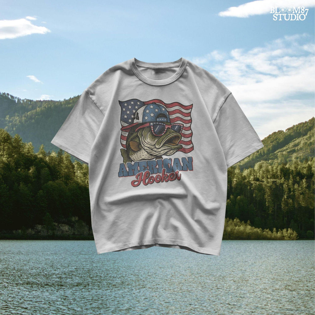 Patriotic cartoon largemouth bass wearing USA sunglasses and a hat in front of the American flag, with the text “American Hooker”.