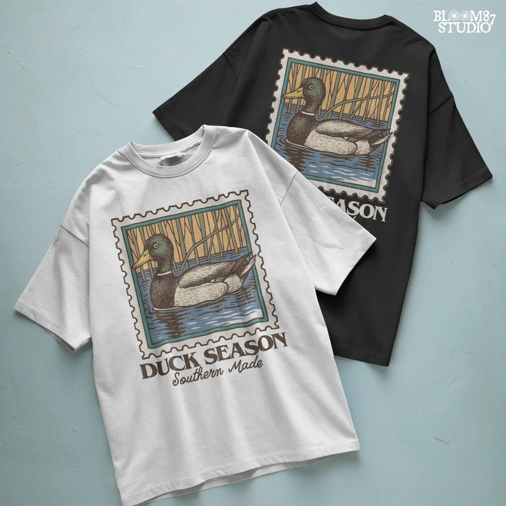 Vintage stamp-style mallard duck floating in water with forest background and text “Duck Season – Southern Made” in retro serif font.