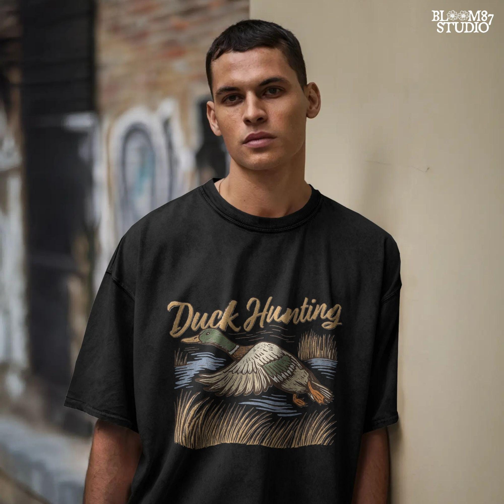 Vintage woodcut-style illustration of a mallard duck flying over marshy water with tall reeds and “Duck Hunting” text in bold script.