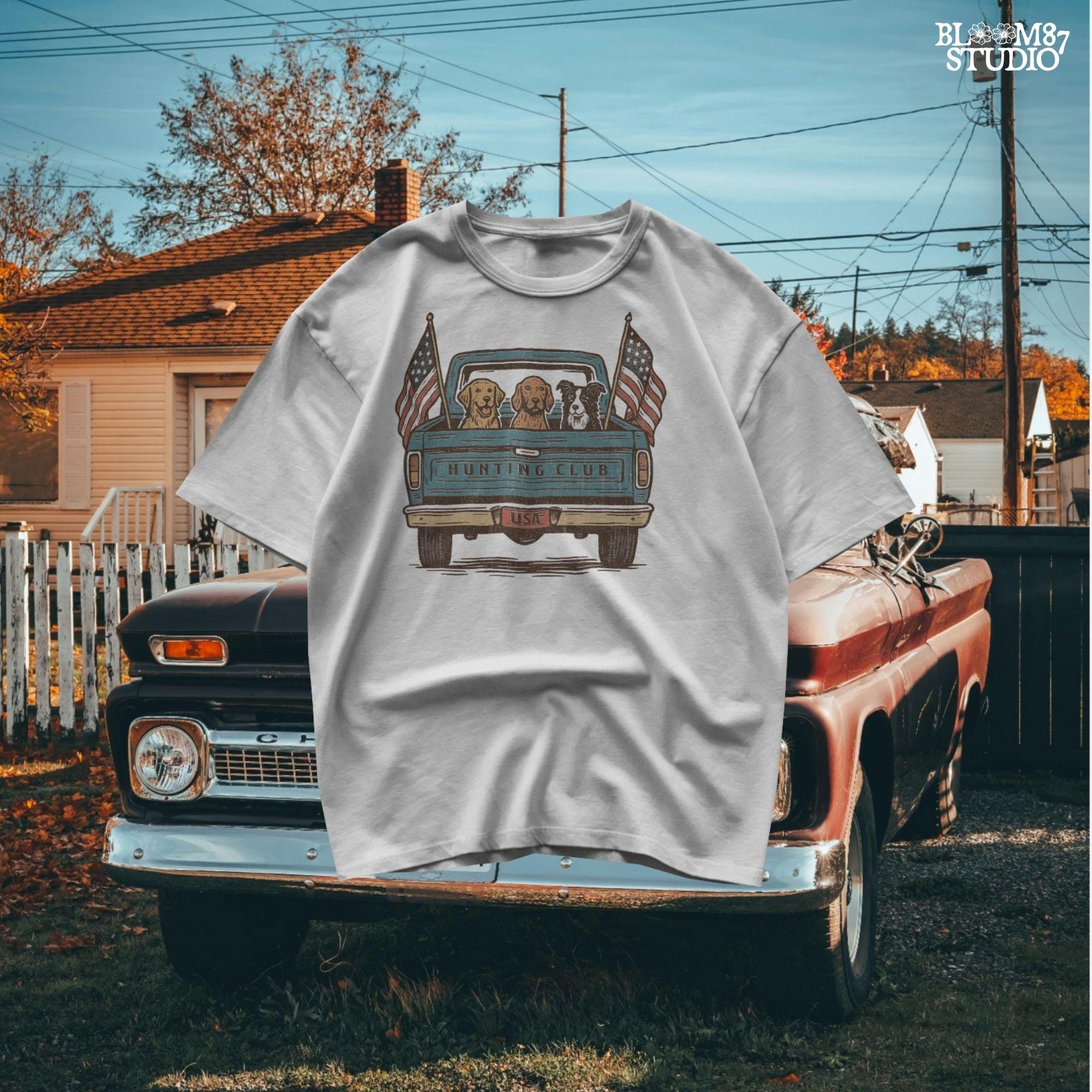 Three hunting dogs in the back of a blue vintage pickup truck with USA flags and “Hunting Club” text, patriotic hunting design for dog lovers.