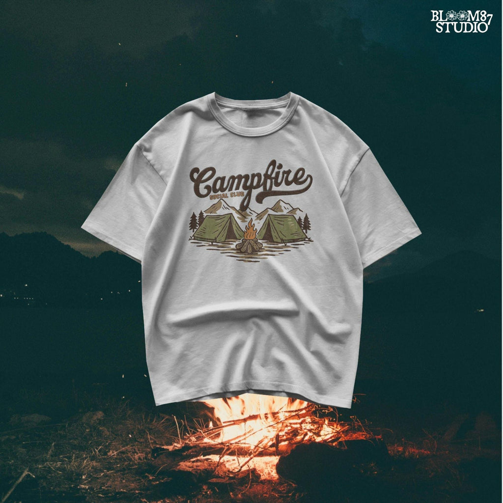 Vintage-style illustration of two camping tents, a lit campfire, pine trees, and mountains with the text “Campfire Social Club.”