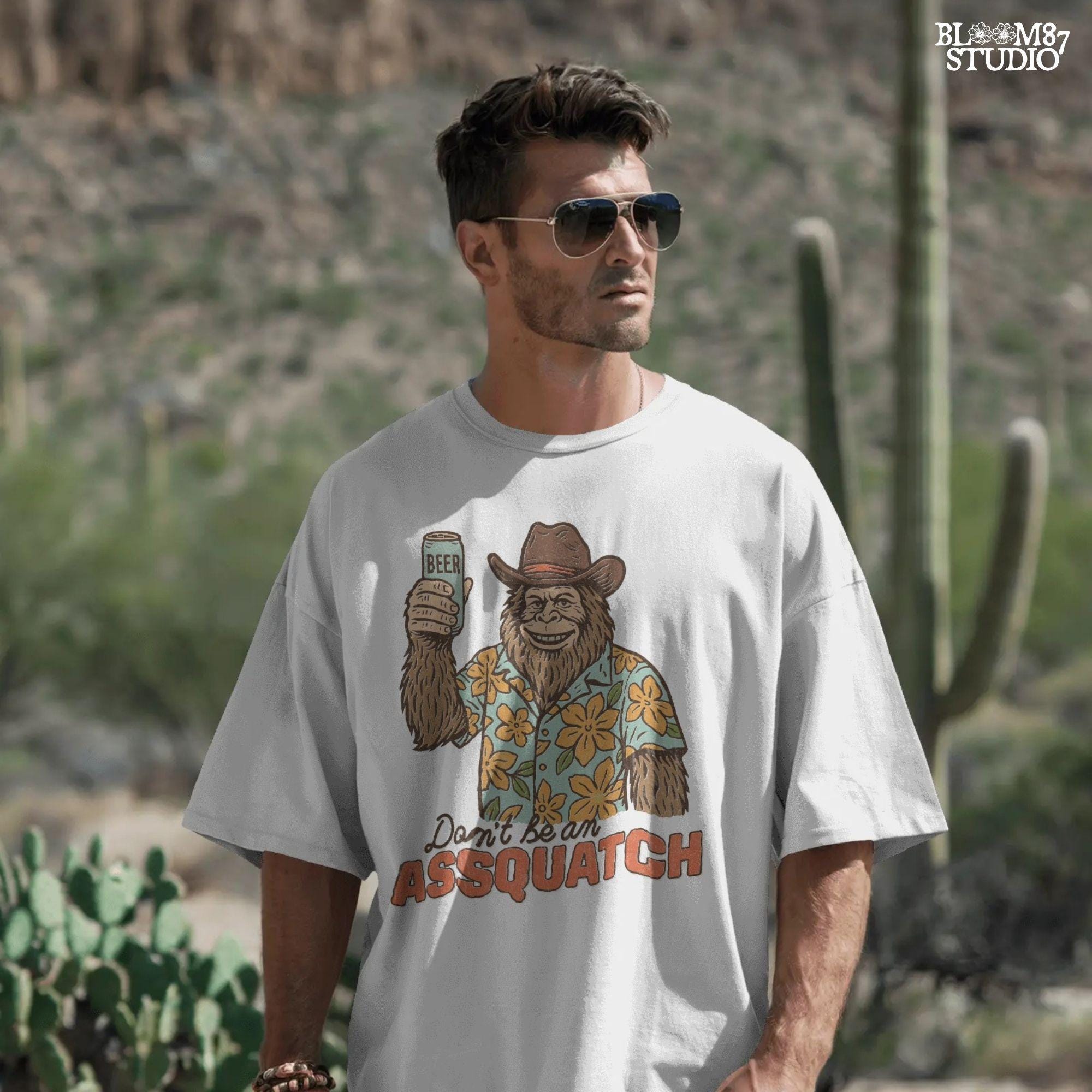 Retro cartoon Sasquatch in floral shirt holding a beer can with text “Don’t Be an Assquatch,” perfect for funny camping or summer designs