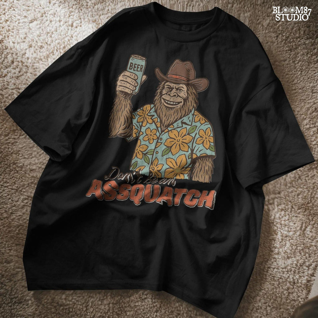 Retro cartoon Sasquatch in floral shirt holding a beer can with text “Don’t Be an Assquatch,” perfect for funny camping or summer designs
