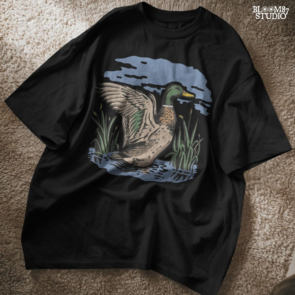 Vintage illustration of a mallard duck with wings spread standing in a pond with reeds and a cloudy blue sky – rustic nature sublimation PNG.